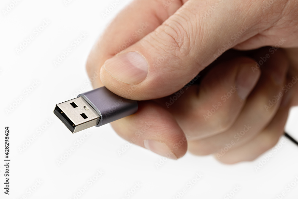 Black USB cable with plug in male hand. Close-up, studio shot Black USB cable with plug in male hand. Close-up, studio shot