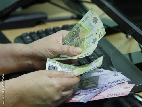 hands of a woman holding Chilean money on a computer keyboard photo