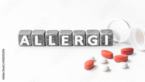 word ALLERGY is made of stone cubes on a white background with pills. medical concept of treatment, prevention and side effects. immune system reaction