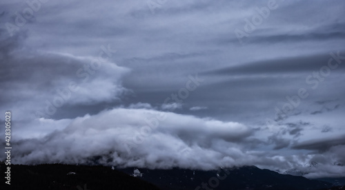 View of Puffy Clouds over the Canadian Mountain Landscape. Colorful Winter Sunset Cloudscape Background. Taken between Squamish and Whistler, British Columbia, Canada.