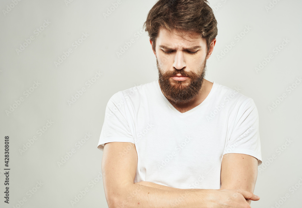 Fototapeta premium a man with a puzzled look looks to the side on a light background and a thick beard