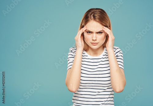 Puzzled woman touches her face with hands on a blue background model stress emotions