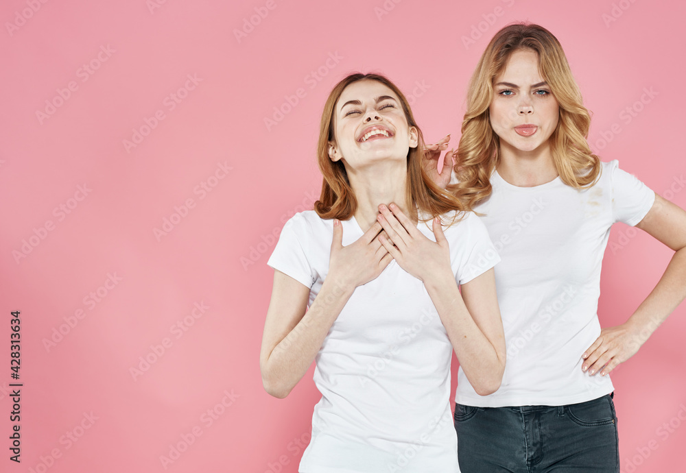 Cheerful women in white T-shirts hugs socializing lifestyle Glamor pink background Cheerful women in white T-shirts hugs socializing lifestyle Glamor pink background