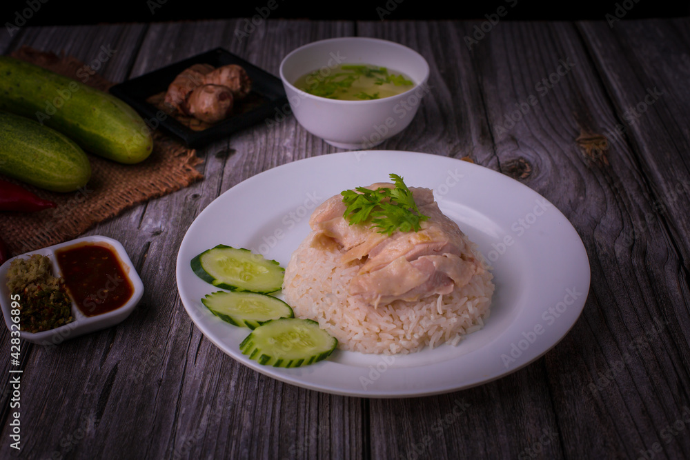 Hainanese chicken rice or Khao Man Gai Asian food in a wood white plate with delicious broth and dipping sauce. Hainanese chicken rice or Khao Man Gai Asian food in a wood white plate with delicious broth and dipping sauce.