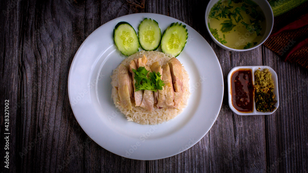 Hainanese chicken rice or Khao Man Gai Asian food in a wood white plate with delicious broth and dipping sauce. Hainanese chicken rice or Khao Man Gai Asian food in a wood white plate with delicious broth and dipping sauce.