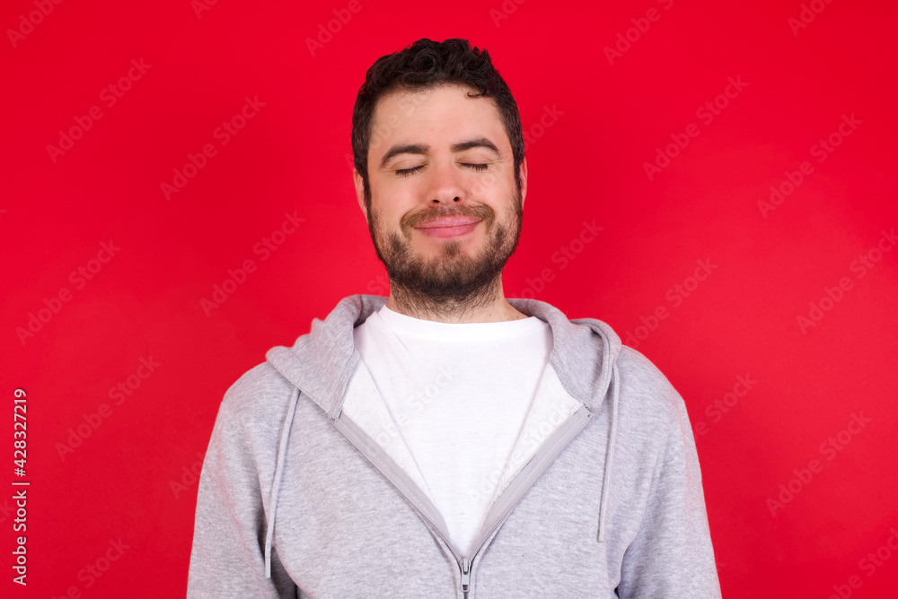 young handsome caucasian man in sports clothes against red background nice-looking sweet charming cute attractive lovely winsome sweet peaceful closed eyes young handsome caucasian man in sports clothes against red background nice-looking sweet charming cute attractive lovely winsome sweet peaceful closed eyes