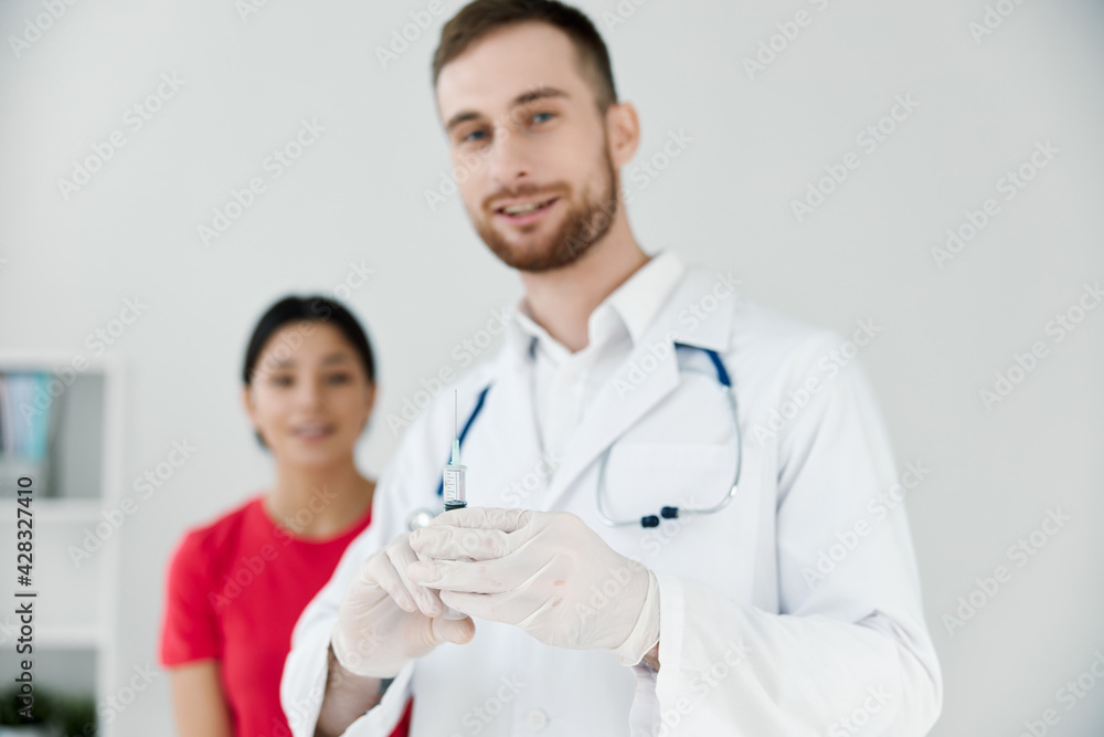 male doctor in white coat female patient in the background male doctor in white coat female patient in the background