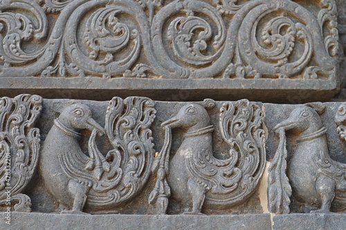 Patterns on the walls of an ancient Indian temple. Stone ornament - Peacocks and flowers. photo