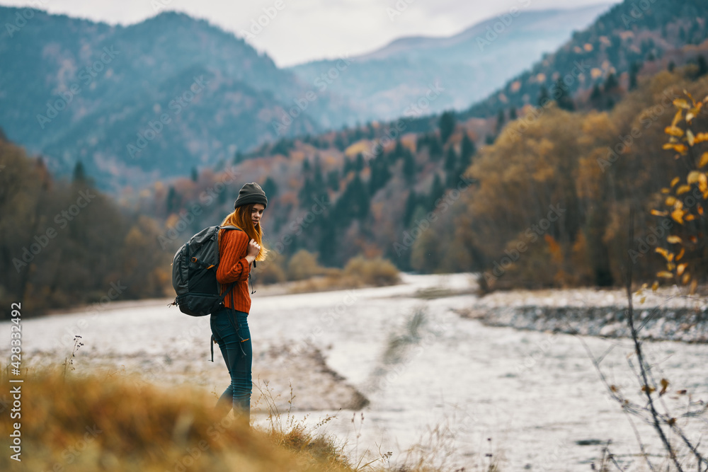 woman with backpack hiking by the river in the mountains landscape