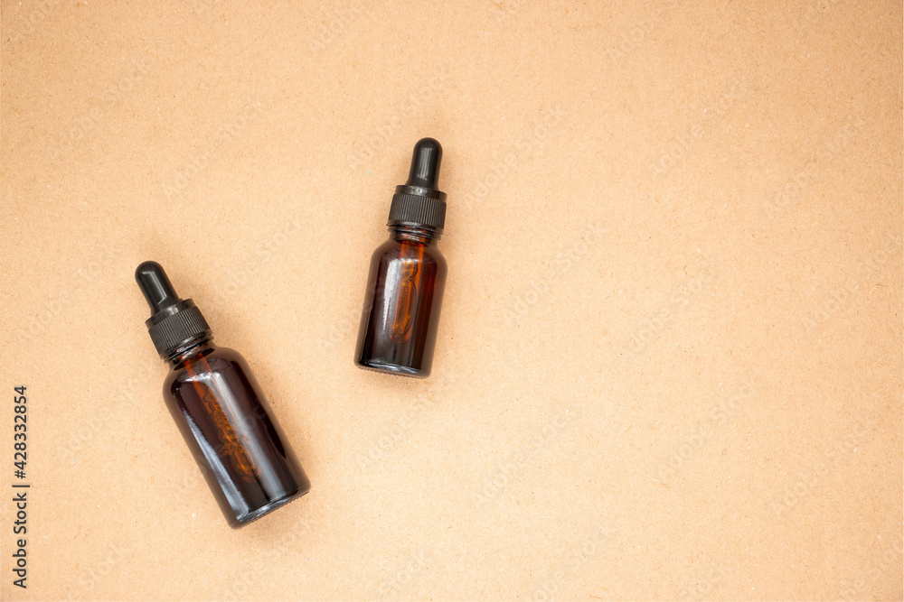 Two amber glass bottles on a beige pastel background. Natural organic eco-cosmetics. Beauty salon branding mockup. Aromatherapy. Two amber glass bottles on a beige pastel background. Natural organic eco-cosmetics. Beauty salon branding mockup. Aromatherapy.