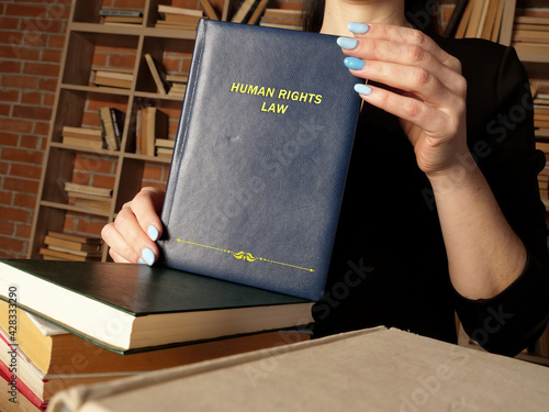 Attorney holds HUMAN RIGHTS LAW book. Human rights law prescribes obligations which states are bound to respect photo