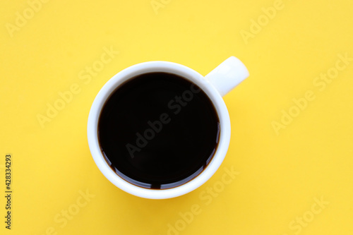 Cup of coffee on a yellow background. Top view, copy space