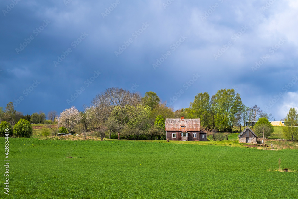 Cottage in a rural landscape with storm clouds on the sky