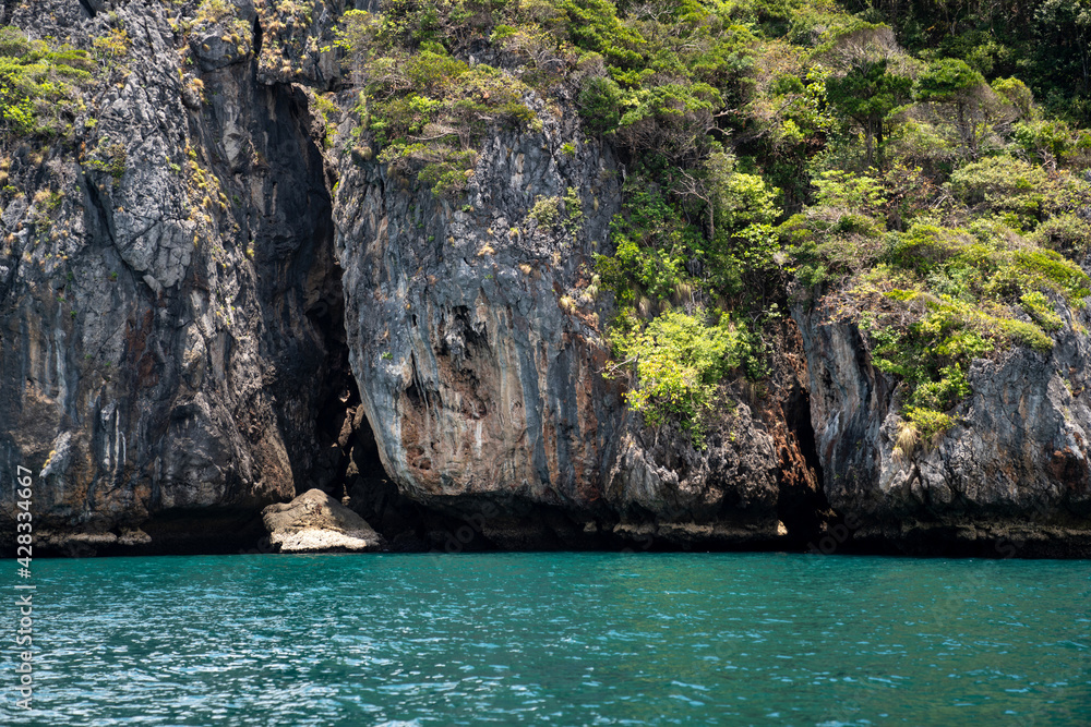 Amazing Large rock cliffs with green tree in the island beach at Thailand. Showing features of sea erosion and cliff recession. Cracks and boulders of rock. Beautiful paradise seascape