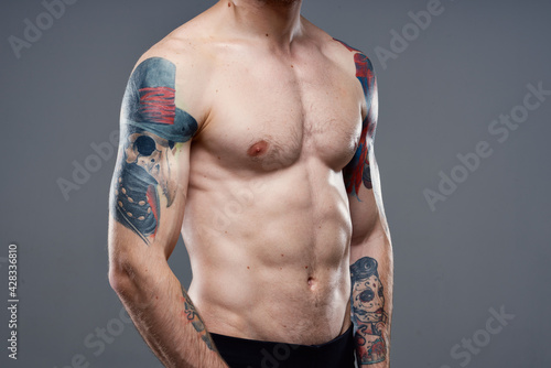 man with tattoos on his arms naked torso pumping up abs workout