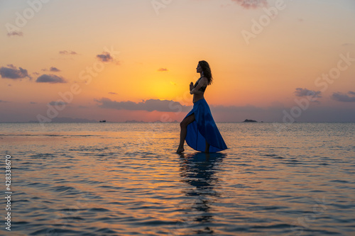 Young beauty girl dancing at tropical beach on sea water at paradise island at sunset. Summer concept © OlegD