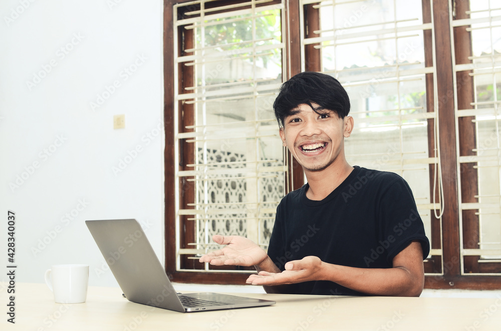 The Asian man was sitting pointing at the laptop The Asian man was sitting pointing at the laptop