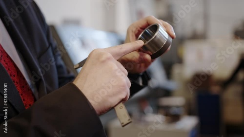 At the factory: A male engineer checks the workmanship of a part with a caliper.