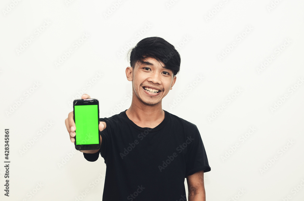 Asian man wearing casual black t-shirt pointing at green screen cellphone Asian man wearing casual black t-shirt pointing at green screen cellphone