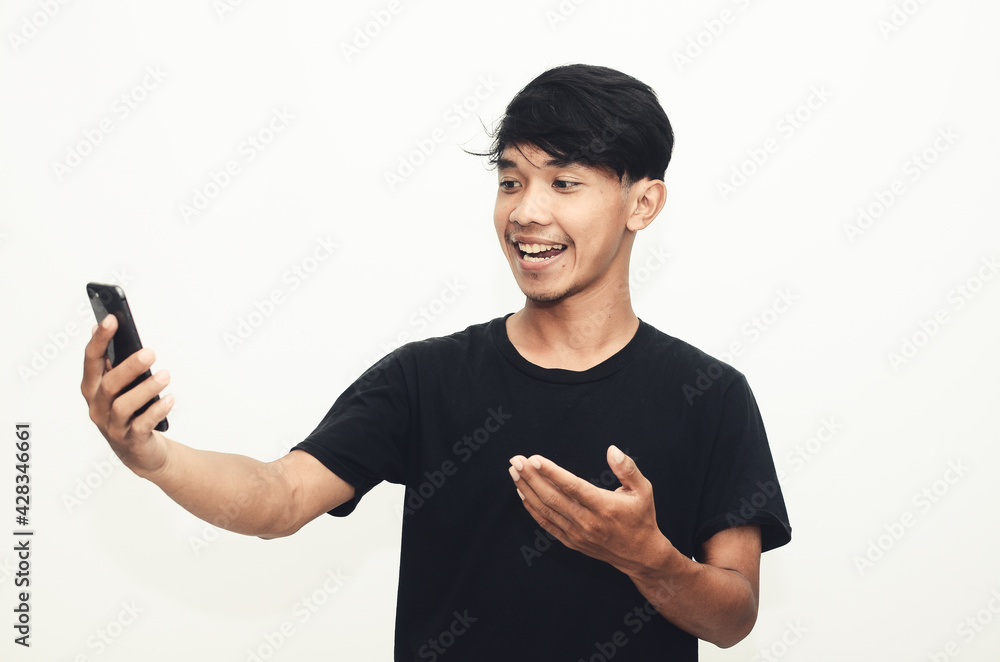 Asian man wearing a casual black shirt pointing at his cellphone Asian man wearing a casual black shirt pointing at his cellphone
