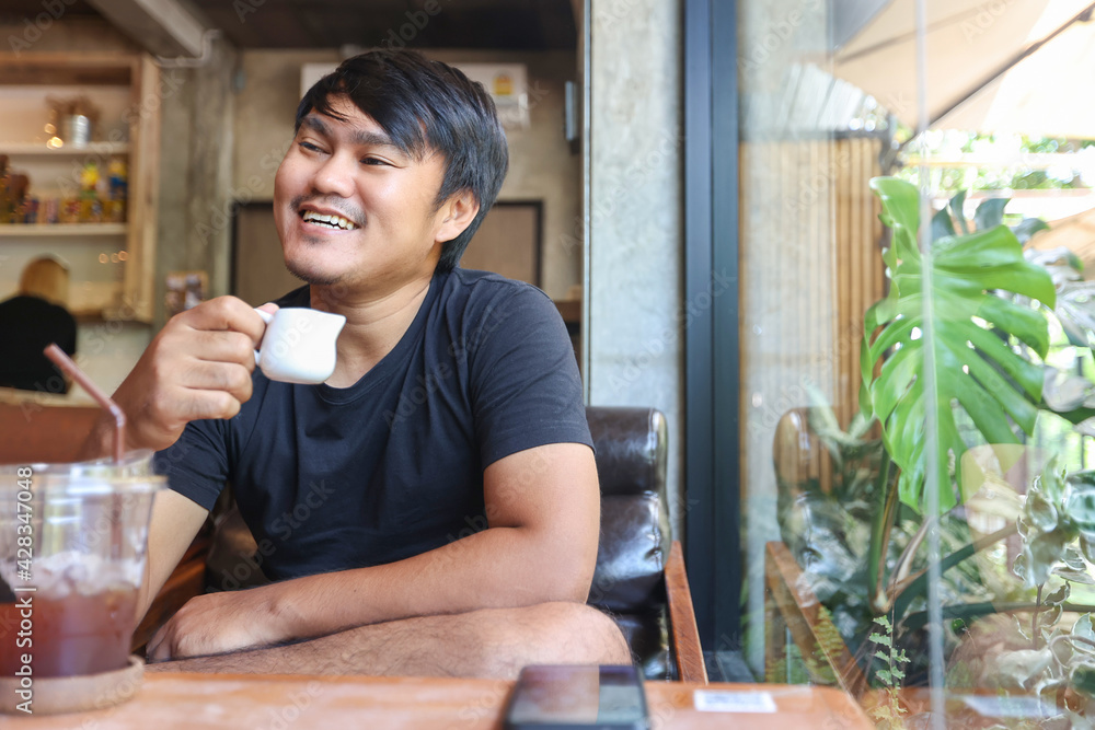 Portrait of asian man sitting in the coffee cafe with using the smartphone. The man smiling in the coffee shop. Portrait of asian man sitting in the coffee cafe with using the smartphone. The man smiling in the coffee shop.