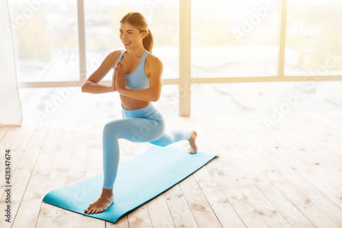 Admirable woman practising yoga in a sunlit room