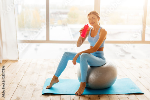 Sporty young lady drinking water during her workout
