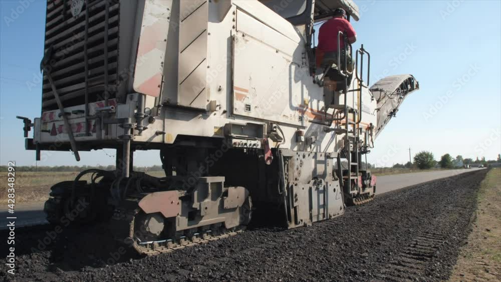 Slow moving of asphalt paver trough a road in sunny summer day Slow moving of asphalt paver trough a road in sunny summer day
