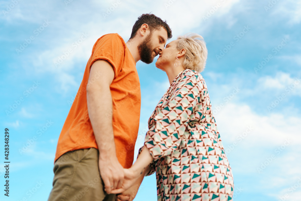 Happy young couple in colorful clothes with sky on background Happy young couple in colorful clothes with sky on background