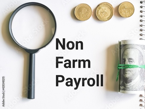 Business and finance concept. Selective focus notebook written NON FARM PAYROLL with coins,fake money and magnifying glass. photo