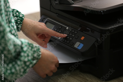 Woman using modern printer in office, closeup