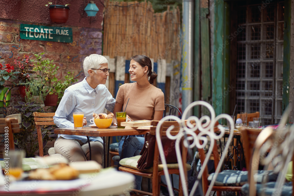 An older woman and her young female friend having a conversation while they have a drink in the bar. Leisure, bar, friendship, outdoor An older woman and her young female friend having a conversation while they have a drink in the bar. Leisure, bar, friendship, outdoor