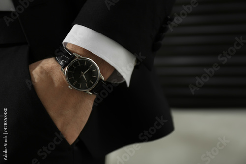 Businessman with luxury wrist watch on blurred background, closeup