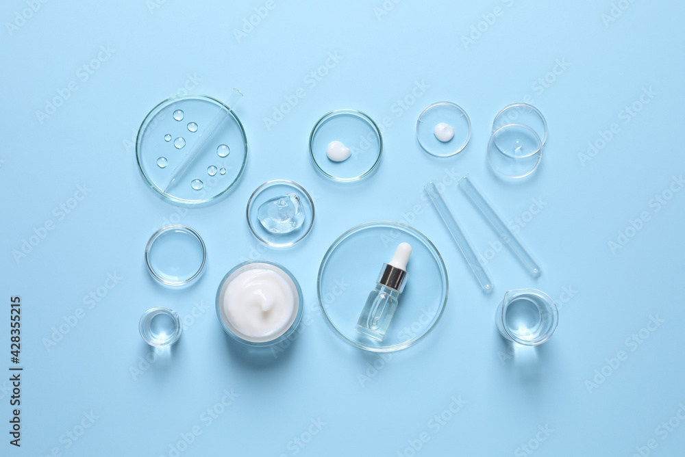 Laboratory glassware and natural ingredients for organic cosmetic product on light blue background, flat lay