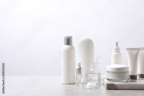 Organic cosmetic products and laboratory glassware on white table, space for text