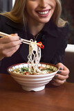 Female hands hold a bowl with Asian traditional soup. Beef pho bo with eggs.