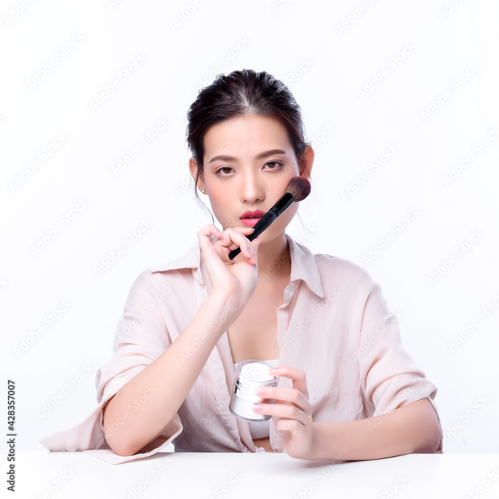 Portrait of beautiful charming young Asian woman posing facial with cosmetic and sitting with white table, beauty of female face with skincare on white background, healthcare and skin care concept. Portrait of beautiful charming young Asian woman posing facial with cosmetic and sitting with white table, beauty of female face with skincare on white background, healthcare and skin care concept.