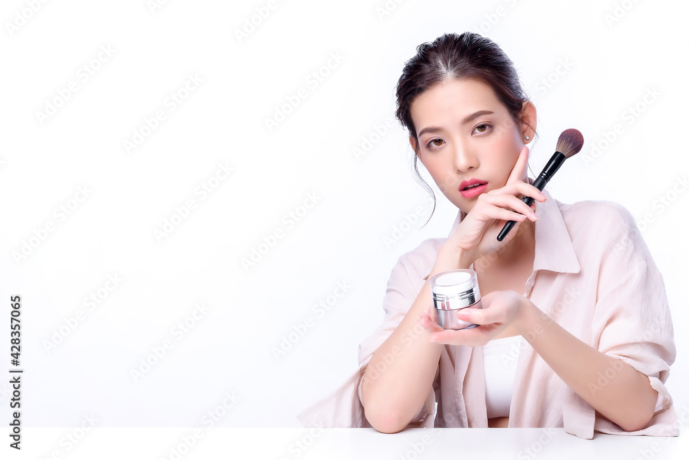 Portrait of beautiful charming young Asian woman posing facial with cosmetic and sitting with white table, beauty of female face with skincare on white background, healthcare and skin care concept. Portrait of beautiful charming young Asian woman posing facial with cosmetic and sitting with white table, beauty of female face with skincare on white background, healthcare and skin care concept.