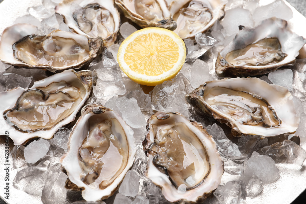 Delicious fresh raw oysters with lemon on ice, closeup Delicious fresh raw oysters with lemon on ice, closeup