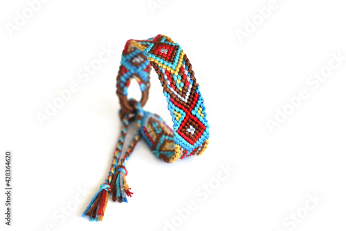 Tied DIY friendship bracelet with Indian colorful pattern handmade of thread on white background