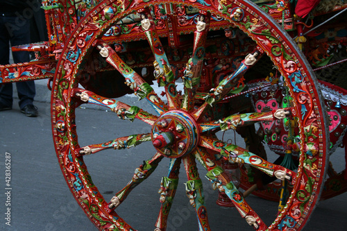 Ruota in legno decorata, tipica di un carretto siciliano, con decorazioni floreali e pupi siciliani, rosse, bianche e verdi  photo