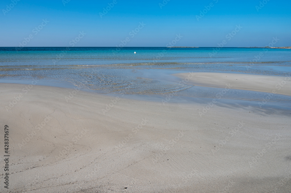 Sabbia bianca con mare trasparente e cielo azzurro.