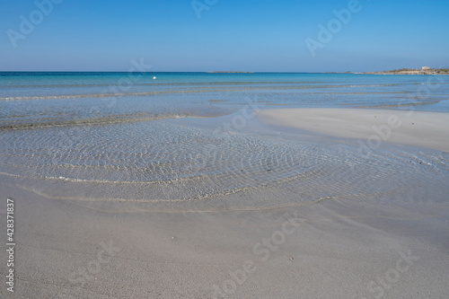 Sabbia bianca con mare trasparente e cielo azzurro.