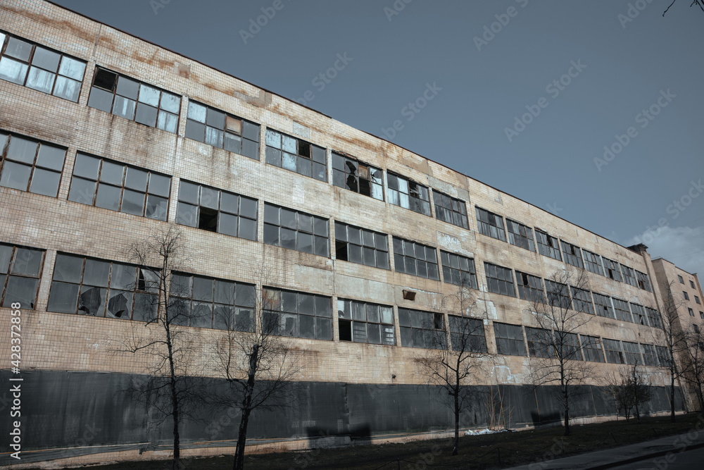 Large abandoned factory. The facade of an abandoned factory with broken windows