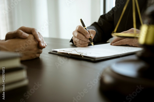 The lawyer is write drafting a legal document while listening to the client's information