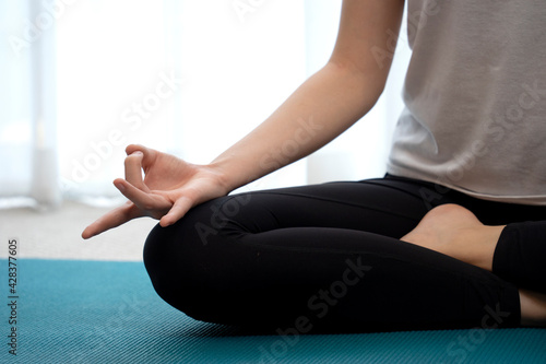 young lady meditating on the mat close up on fingers in yoga