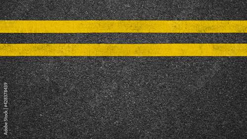 Surface grunge rough of asphalt, Dark grey with double yellow line on the road and small rock, Texture Background, Top view © Jomic