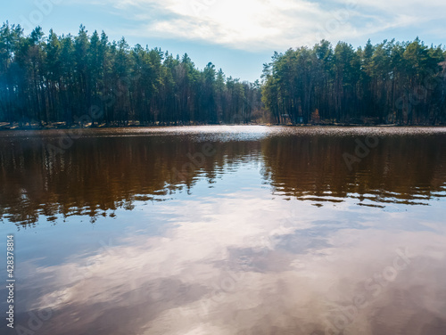 Beautiful spring lake in the forest. Sunshine reflection on the water. Nature and travel concept.