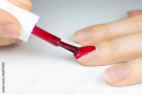 Woman applies red nail polish..Girl making a manicure. Salon procedures at home. Beautiful hands and nails. Close up  macro photo.