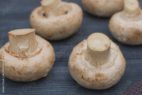 Fresh champignon mushrooms lie on a gray wooden table.